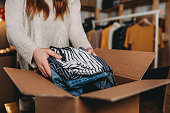 A millennial woman is preparing the shipment of some clothes in her new online shop