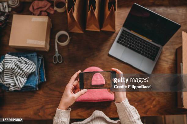 a woman is photographing a pink hat to post a new item on her online shop - secondhand försäljning bildbanksfoton och bilder