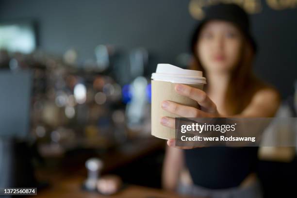 woman barista serving coffee in takeaway paper disposable cups - takeaway coffee stockfoto's en -beelden