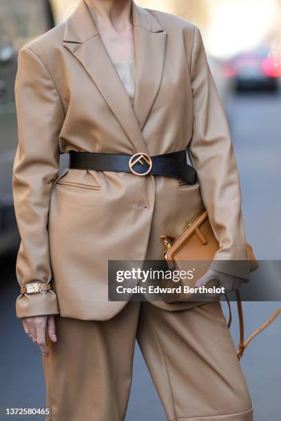 Guest wears a beige shoulder-off t-shirt, a brown shiny leather blazer jacket, matching brown shiny leather shorts, a black shiny leather with gold...