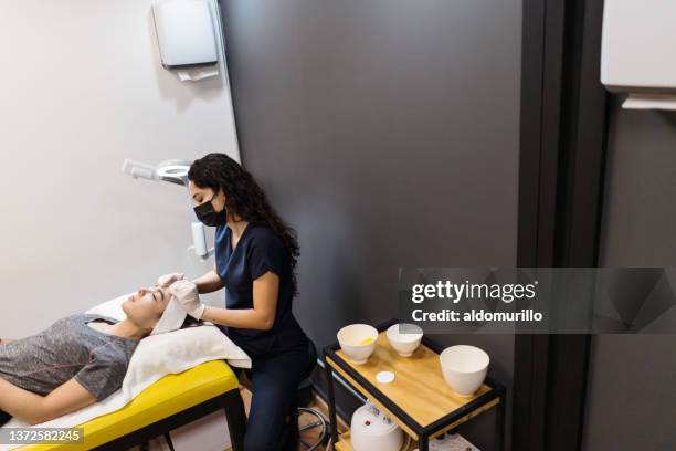 esthetician massaging woman's face - schoonheidsspecialist stockfoto's en -beelden