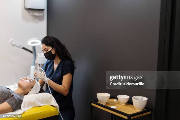 esthetician using device on woman's face - esthetician stock pictures, royalty-free photos & images