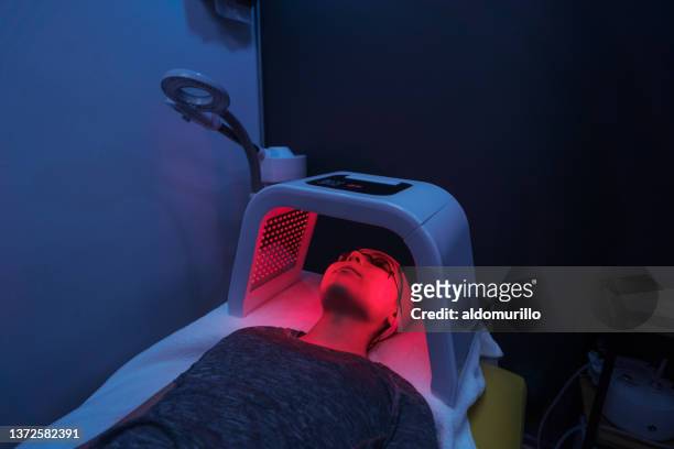 young woman doing red light therapy on face - alternative therapy stock pictures, royalty-free photos & images