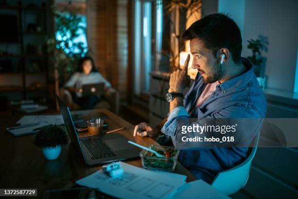 man having late dinner during video call conversation. - working late imagens e fotografias de stock