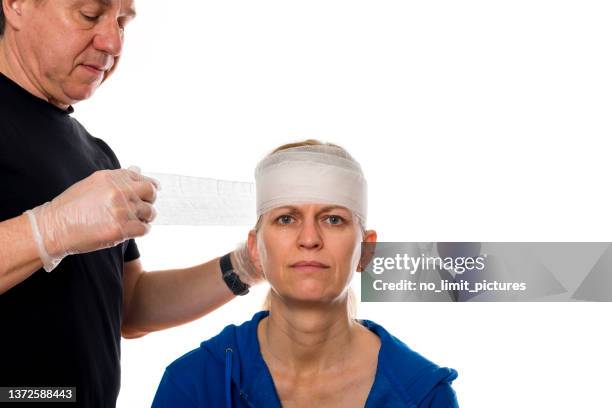 mann bandagiert den verletzten kopf einer frau - head bandage stock-fotos und bilder