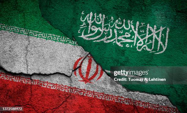 full frame photo of weathered flags of iran and saudi arabia painted on a cracked wall. - saudi arabian flag stockfoto's en -beelden