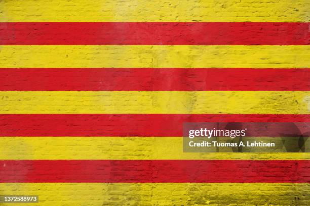 full frame photo of a weathered flag of catalonia painted on a plastered brick wall. - comunidad autónoma de cataluña 個照片及圖片檔