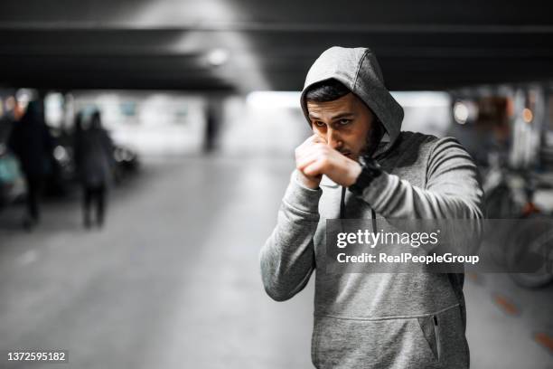 young muscular sportsman sparring in underground garage. - fighting stance stock pictures, royalty-free photos & images