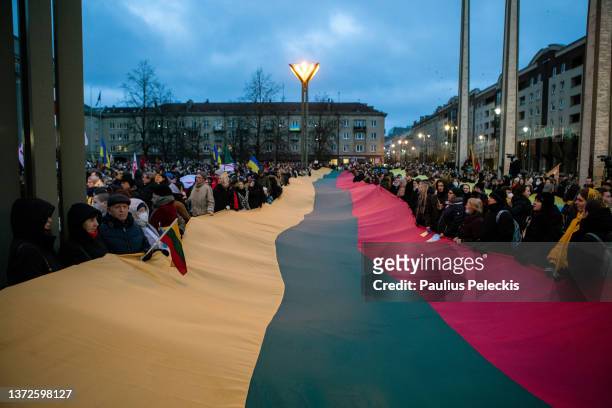 People hold a giant Lithuanian flag during a protest against Russia's attack on Ukraine near the Russian Embassy, on February 24, 2022 in Vilnius,...