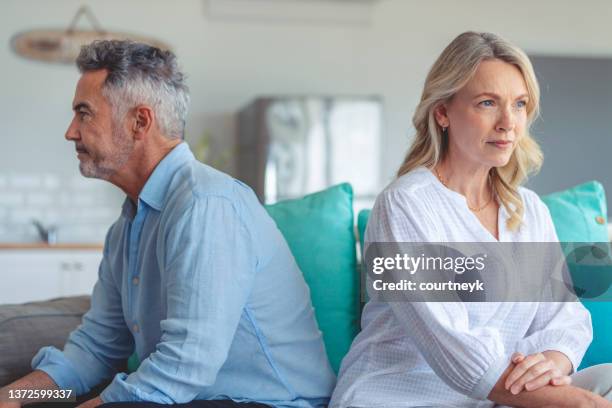 mature couple fighting at home sitting on the sofa. - jealous wife stock pictures, royalty-free photos & images