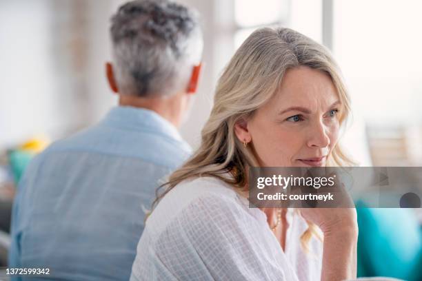 mature couple fighting at home sitting on the sofa. - jealous wife stock pictures, royalty-free photos & images