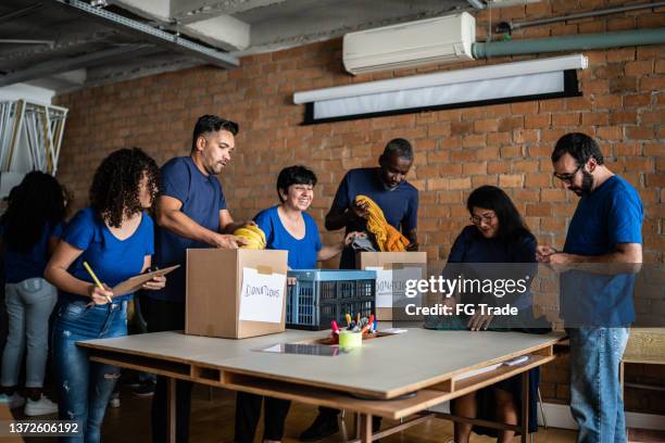 volunteers arranging donations in a community charity donation center - distribution center stockfoto's en -beelden