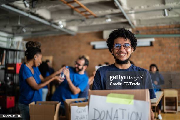 retrato de un joven sosteniendo una caja de caridad - evento de beneficencia fotografías e imágenes de stock