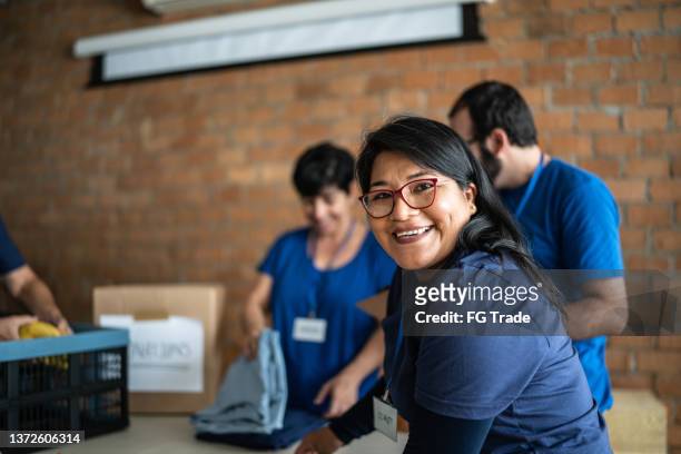 retrato de un voluntario que trabaja en un centro de donación de caridad comunitaria - benefits fotografías e imágenes de stock