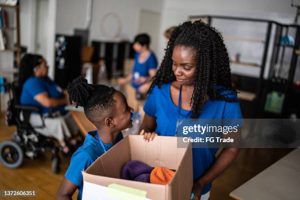 mother and son holding a donation box - kids at community center stock pictures, royalty-free photos & images