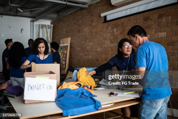 volunteers arranging clothes for donation in a community center - homeless shelter stock pictures, royalty-free photos & images