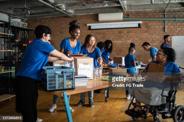 volunteers arranging donations in a community center - including a disabled person - community events stockfoto's en -beelden