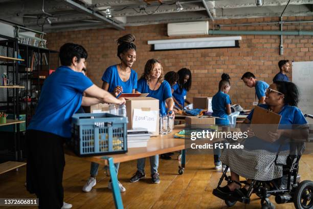 volunteers arranging donations in a community center - including a disabled person - donation box stock pictures, royalty-free photos & images