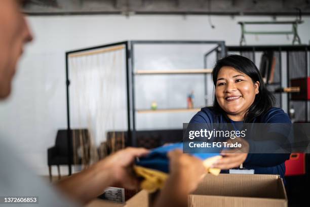 voluntario dando donaciones a un hombre en un centro comunitario - humility fotografías e imágenes de stock