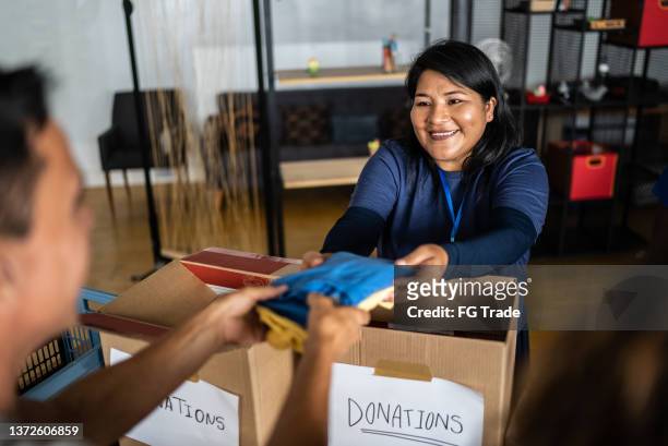 volunteer giving donations to a man at a community center - shelter imagens e fotografias de stock
