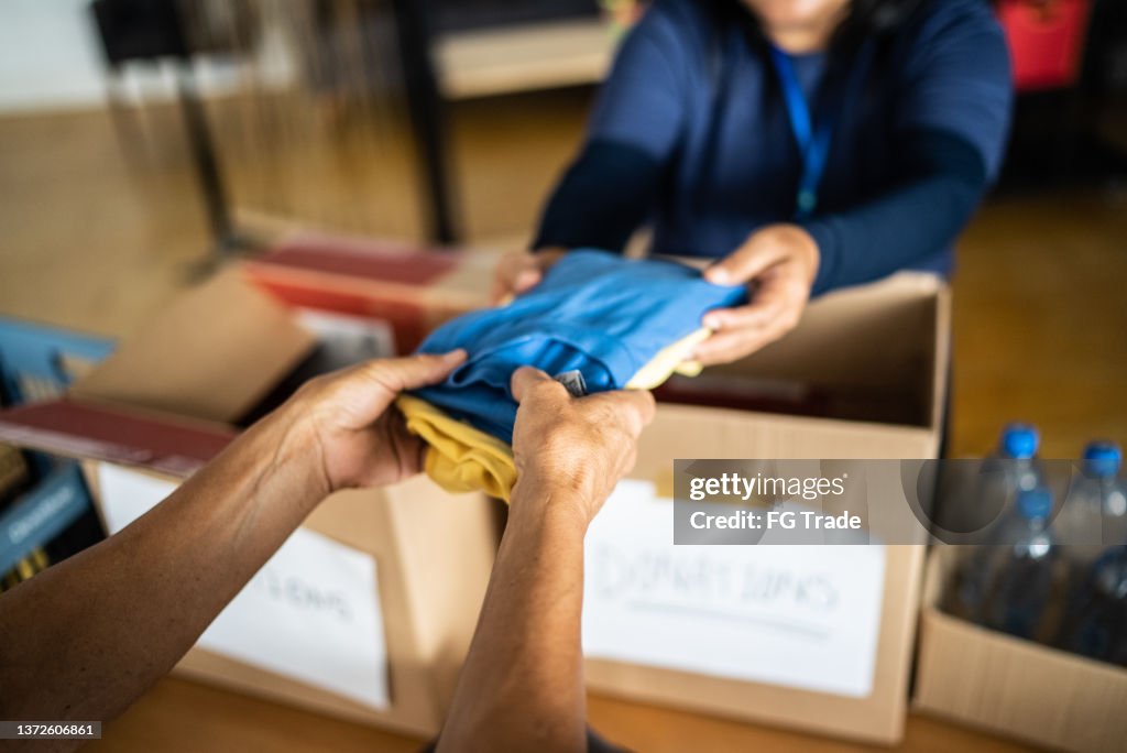 Volunteer's hand giving donations to a person at a community center