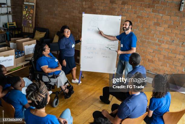 mid adult man talking in a meeting at a community center - including a disabled person - vrijgevigheid stockfoto's en -beelden