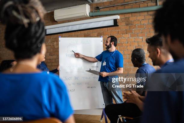 mid adult man talking in a meeting at a community center - showing empathy stock pictures, royalty-free photos & images