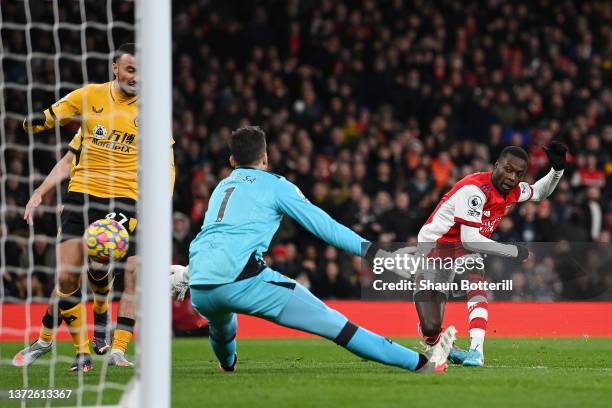 Nicolas Pepe of Arsenal scores their sides first goal past Jose Sa of Wolverhampton Wanderers during the Premier League match between Arsenal and...
