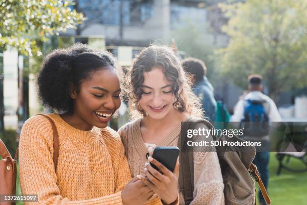 cheerful teenagers look at social media before school - 17 stockfoto's en -beelden