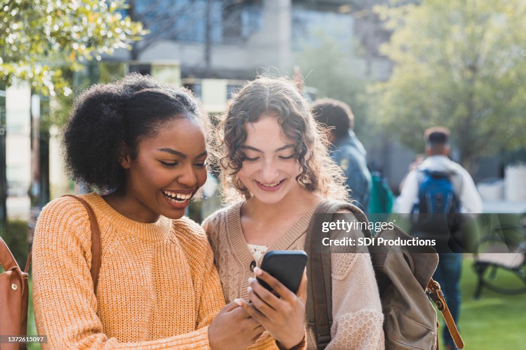 Cheerful teenagers look at social media before school