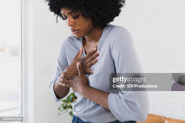 mid adult woman holds chest - borstkas stockfoto's en -beelden