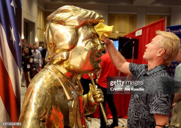 Artist Tom Zegan uses a cloth to wipe down the statue he created of former U.S. President Donald Trump at the Conservative Political Action...