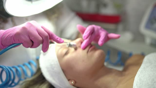 Beautician doing a microdermabrasion treatment on a female client's face
