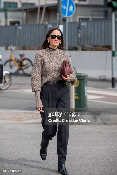 Guest is seen wearing brown bag, dark denim jeans, jumper outside Sunnei fashion show during the Milan Fashion Week Fall/Winter 2022/2023 on February...
