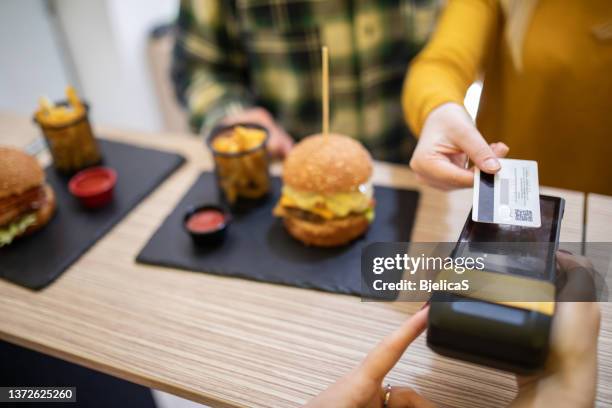 young woman making contactless payment for burgers in fast food restaurant - small business lunch stock pictures, royalty-free photos & images