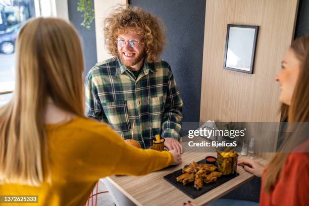 the waitress bringing a hamburger to a friends in the fast food restaurant - fried chicken burger stock pictures, royalty-free photos & images