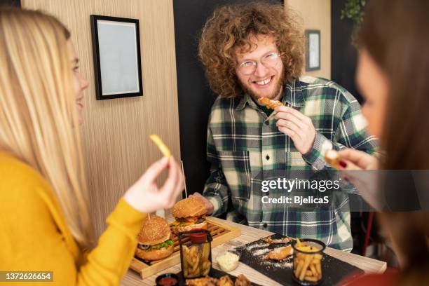 drei freunde genießen ihre gemeinsame zeit im fast-food-restaurant - eating chicken stock-fotos und bilder