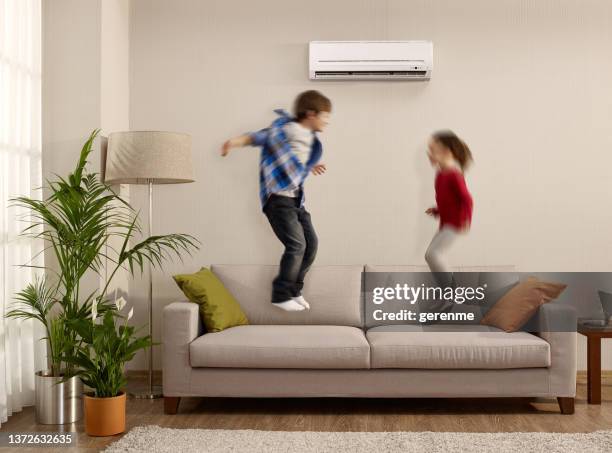 kids jumping on a sofa - airco stockfoto's en -beelden