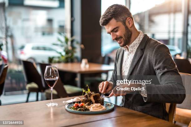 happy young man eating lunch at a restaurant. - costeleta comida imagens e fotografias de stock