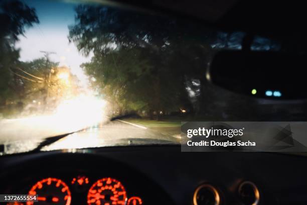 dashboard view of a moving car with bright headlights - rain night ストックフォトと画像