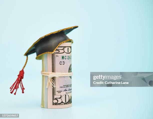 cost of education. money roll wearing a mortarboard graduation cap - 50 dollar bill stock pictures, royalty-free photos & images