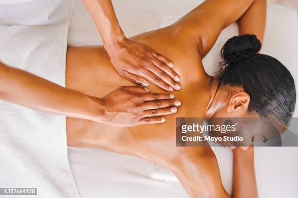 shot of an attractive young woman getting a massage at a spa - massajar imagens e fotografias de stock