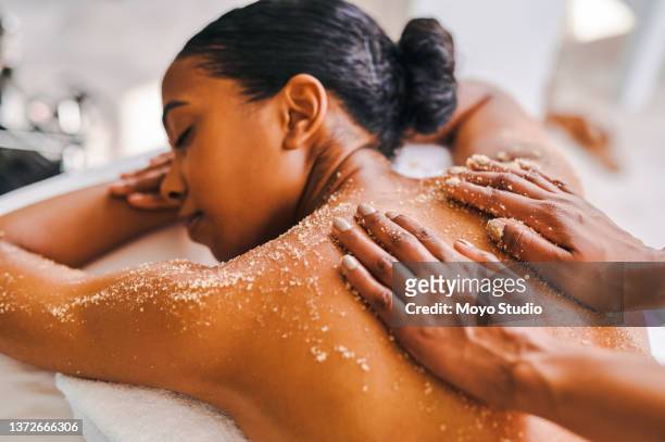 shot of an attractive young woman getting an exfoliating massage at a spa - massage black woman stock pictures, royalty-free photos & images
