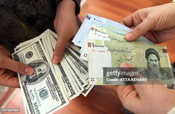 This picture illustrates Iranians on January 12, 2012 counting and exchanging the United States 100-dollar bills and Iran's Rial banknotes, bearing a...