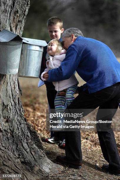 Sunday, Maple Sugaring Days at Brookwood Farms in the Blue HIlls. Peter Babachicos, of Milton, lifts up his grandaughter Ava Day to get a peek inside...