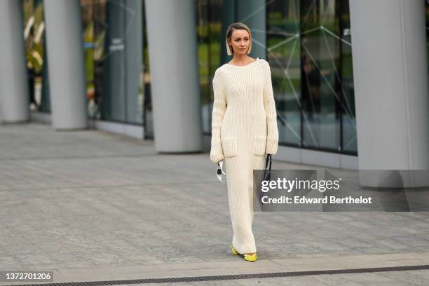 Nataly Osmann wears a white latte ribbed wool long sleeves / pockets / long wool dress, white sunglasses, a black leather and embroidered rhinestones...