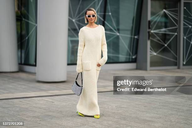 Nataly Osmann wears a white latte ribbed wool long sleeves / pockets / long wool dress, white sunglasses, a black leather and embroidered rhinestones...