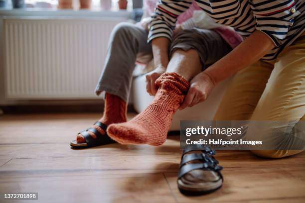 close-up of healthcare worker putting on warm socks to senior woman. - carer stock-fotos und bilder