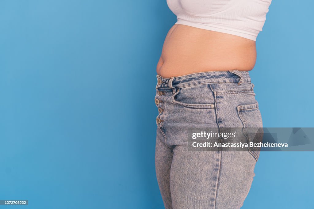 Overweight girl in gray jeans against a blue background