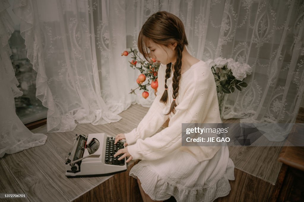 Girl Using Typewriter A Beautiful Asian Girl Typing On A Typewriter Near The Windowsill High ...